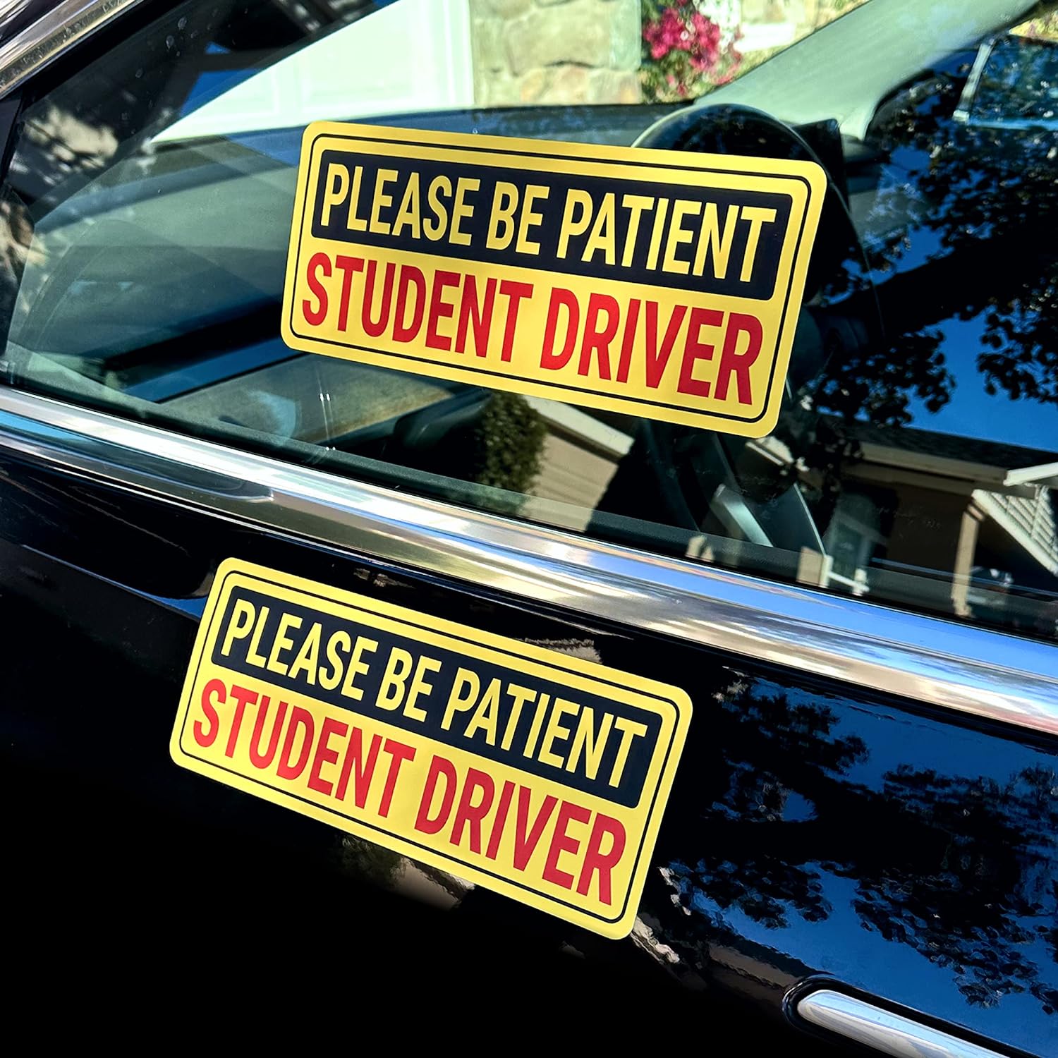 two student driver stickers on a tesla. One on the window, and one on the body of the car.